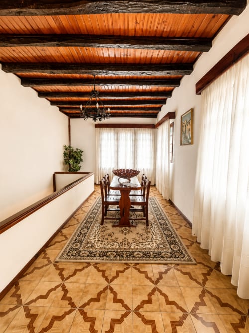 Elegante corredor de jantar da Pousada Serrana Gerês com vigas de madeira aparente, soalho em padrão geométrico e mesa posta
