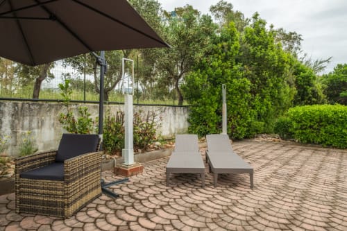 Giardino terrazza di House Live Express Quartu Sant'Elena con lettini, ombrellone e lussureggiante vegetazione