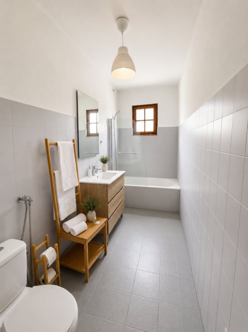 Banheiro moderno da Pousada Serrana Gerês com azulejos brancos, móvel de madeira, banheira e iluminação pendente