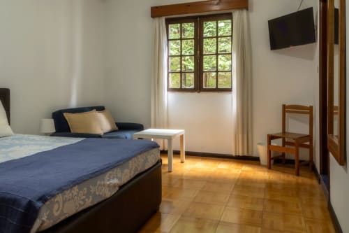 Espaçoso quarto triplo na Pousada Serrana Gerês com vista para a montanha, cama, área de estar e comodidades modernas