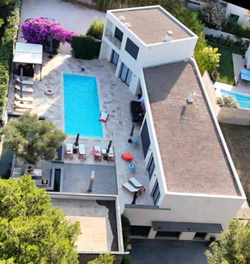 Vue aérienne de La Villa Monarque à Cap d'Agde avec piscine, transats et bâtiment blanc moderne
