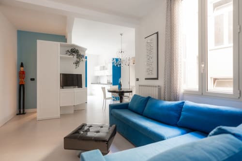 Soggiorno moderno con divano blu, cucina bianca e vista città a Perla Marina, Finale Ligure