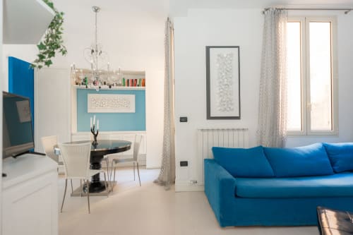 Elegante salotto moderno con divano blu, scrivania da lavoro e vista sulla città presso Perla Marina a Finale Ligure