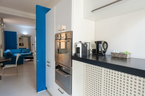 Cucina moderna nell'appartamento Perla Marina, Finale Ligure, con elettrodomestici in acciaio inox e parete azzurra