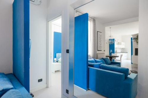 Luminosa zona living moderna in blu e bianco con divano, cucina a vista e vista sulla città a Perla Marina, Finale Ligure