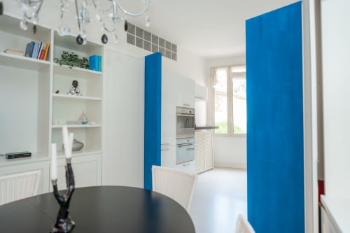 Moderna zona cucina-pranzo con cabinetry bianca, pannelli blu e vista sulla città nell'appartamento Perla Marina, Finale Ligure