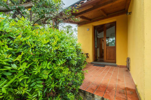 Patio in terracotta giallo con siepi da giardino e porta in legno all'ingresso di House Live Express, Quartu Sant'elena