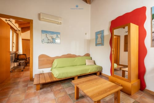 Luminosa camera ospiti con divano futon verde lime, mobili in legno e specchio con cornice rossa all'House Live Express, Quartu Sant'Elena