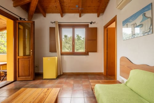 Spaziosa Suite Locandiere 2 presso House Live Express con travi in legno, divano verde, frigorifero giallo e vista sul giardino a Quartu