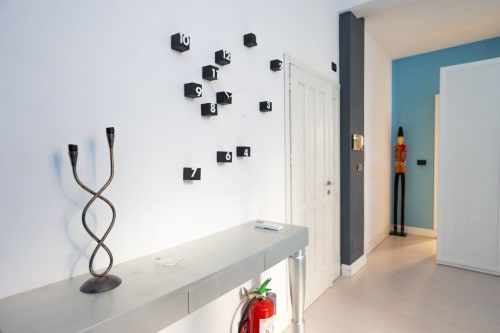 Corridoio moderno dell'appartamento Perla Marina a Finale Ligure, con parete con orologio artistico e arredamento contemporaneo