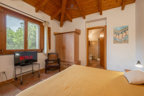 Suite Locandiere con 2 camere presso House Live Express: letto matrimoniale, TV a schermo piatto, armadio in legno e vista giardino a Quartu