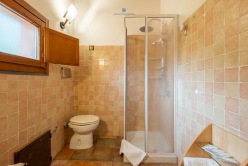 Bagno moderno con cabina doccia, WC e pareti rivestite in cotto presso l'hotel House Live Express a Quartu Sant'Elena,