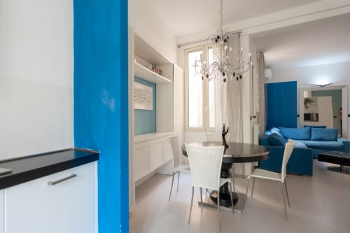 Moderna zona pranzo con accenti blu, lampadario di cristallo e vista sulla città a Finale Ligure