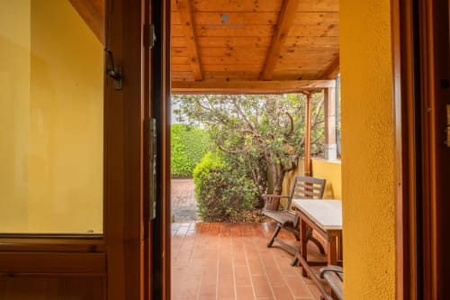 Terrazza Locandiere Suite 2 con vista giardino, pavimento in cotto, arredi in legno e siepi rigogliose presso House Live Express, Quartu