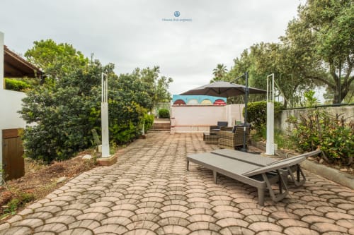 Terrazza giardino della House Live Express a Quartu Sant'Elena con patio pavimentato, lettini e vegetazione tropicale