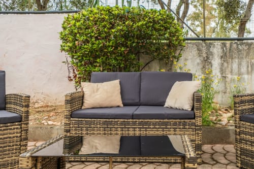Spazio esterno con posti a sedere presso House Live Express: divano in vimini, cuscini e lussureggiante siepe verde a Quartu Sant'Elena