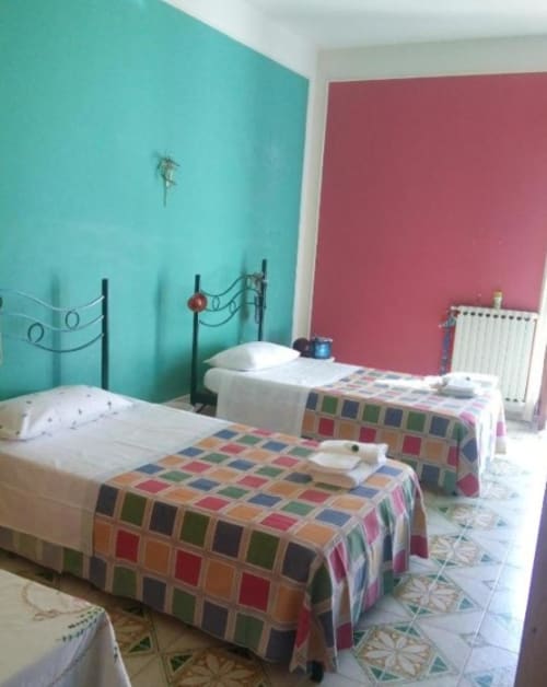 Camera da letto colorata a Bienbi Woods Three Houses con pareti turchesi e rosa, letti gemelli con coperte patchwork