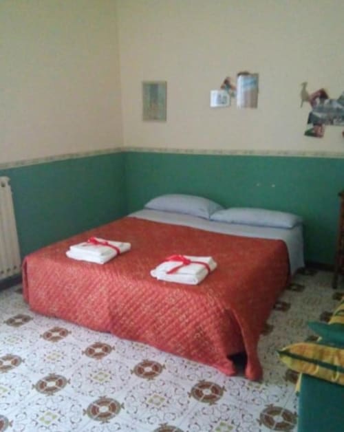 Camera da letto del cottage Bienbi Woods a Boscotrecase con copriletto rosso, cuscini blu, pareti verdi e pavimento decorato