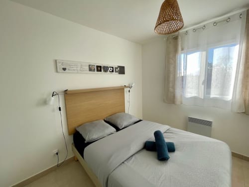 Bright bedroom at Résidence Marina di Bravone with wooden bed, white linens, and large windows overlooking the sea