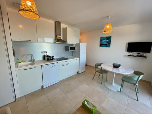 Modern apartment kitchen and dining area at Résidence Marina di Bravone, Linguizzetta with white cabinetry and sea view