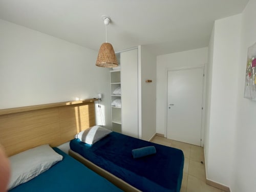 Modern bedroom at Résidence Marina di Bravone with wooden bed, woven pendant light, and built-in storage in Linguizzetta