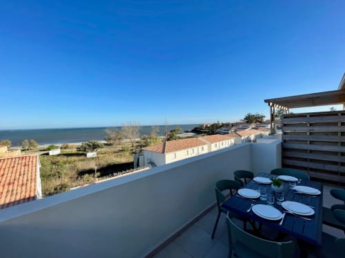 Rooftop terrace at Résidence Marina di Bravone in Linguizzetta with dining table, sea view, and coastal landscape