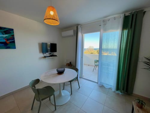 Modern apartment at Marina di Bravone with round dining table, sea view balcony, and coastal scenery in Linguizzetta