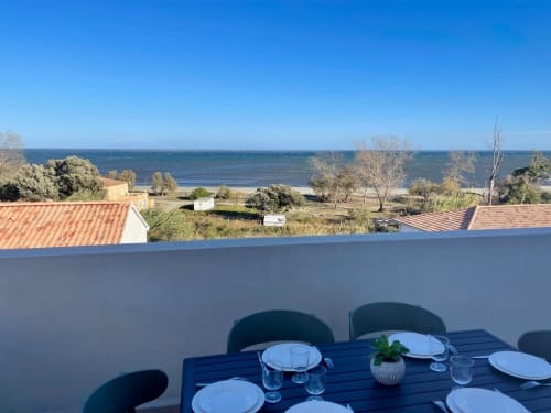 Dining terrace at Marina di Bravone overlooking bay, laid table with sea view, Corsica