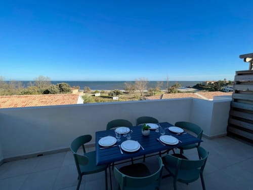 Rooftop terrace at Marina di Bravone with dining table, ocean views, and Corsican coastline