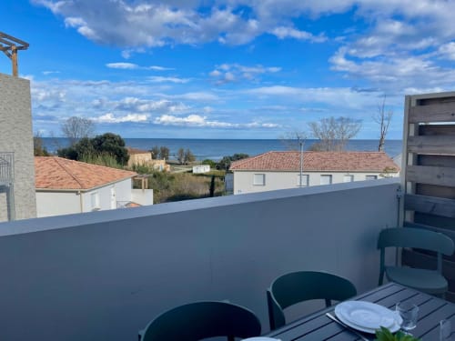 Vue sur la terrasse de la Résidence Marina di Bravone en Corse avec vue sur mer, mobilier contemporain et architecture côtière