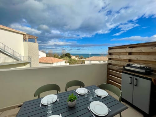 Terrazza fronte mare di Résidence Marina di Bravone con zona pranzo con vista sul mare, barbecue esterno e costa mediterranea