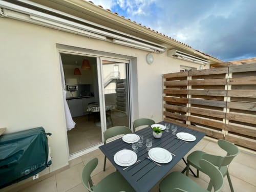 Terrazza panoramica della Résidence Marina di Bravone con tavolo da pranzo, sedie verdi e recinzione in legno