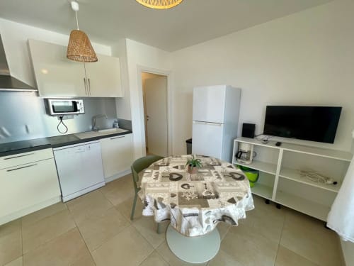 Cucina open-plan e zona pranzo dell'appartamento Marina di Bravone a Linguizzetta con tavolo da pranzo, arredamento bianco e TV