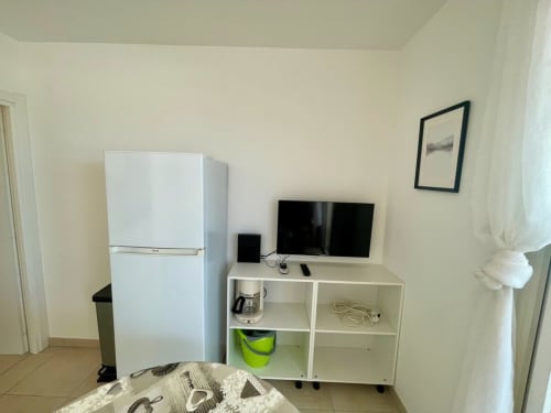 Moderna cucina attrezzata presso la Résidence Marina di Bravone con frigorifero bianco, TV e ripiani contenitori a Linguizzetta
