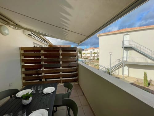 Area pranzo sul balcone della Résidence Marina di Bravone con tenda retrattile, tavolo nero e vista sul mare