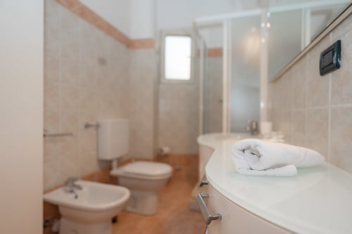 Bagno moderno nell'appartamento Perla Marina a Finale Ligure, con doccia, wc, bidet e asciugamani piegati