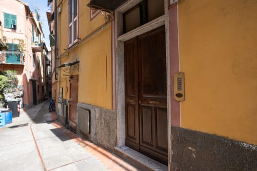 Affascinante via stretta a Varigotti con edificio giallo e porte in legno marrone, Finale Ligure Italia