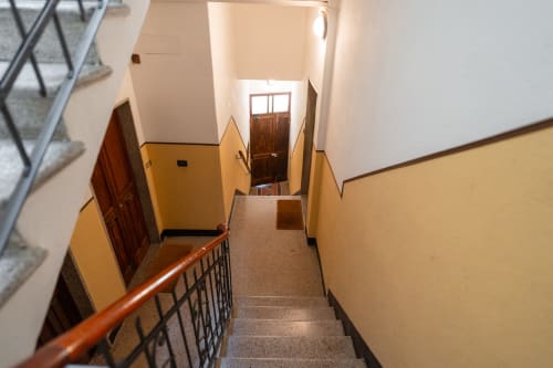 Luminosa scala con pareti gialle e ringhiere in legno presso l'hotel Welcome Holiday a Finale Ligure, Italia