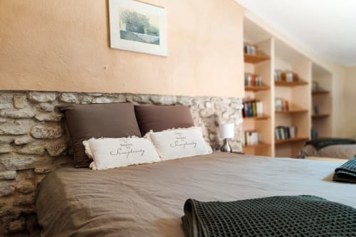 Chambre accueillante au Gîte Lavande de Domaine Bellavigne avec mur en pierre, étagères en bois et vue sur le jardin à Forcalquier