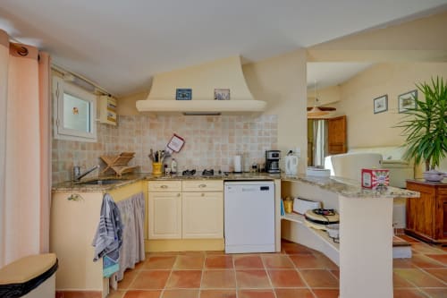 Cuisine ensoleillée du gîte Lavande à Domaine Bellavigne avec armoires crème, carrelage en terre cuite et vue sur le jardin à Forcalquier