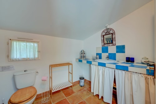 Salle de bain aux carrelages bleu et blanc du gîte Lavande au Domaine Bellavigne à Forcalquier, avec toilettes et lavabo en bois