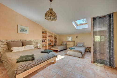Chambre spacieuse au Gîte Lavande du Domaine Bellavigne à Forcalquier, avec plusieurs lits, puits de lumière et vue sur le jardin