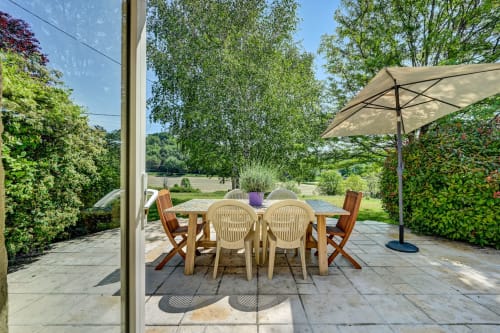 Terrasse extérieure du Gîte Lavande à Domaine Bellavigne avec table à manger, parasol crème et vue sur le jardin à Forcalquier