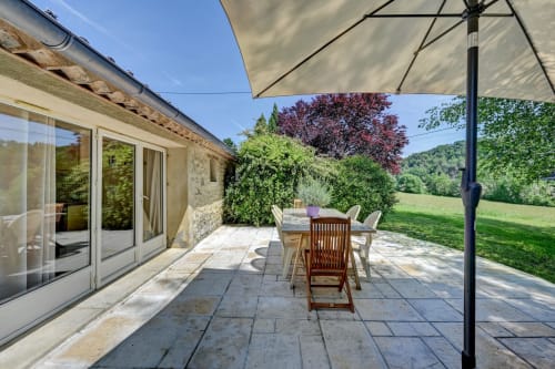 Terrasse spacieuse du Gîte Lavande à Domaine Bellavigne à Forcalquier avec coin repas, parasol et vue sur le jardin