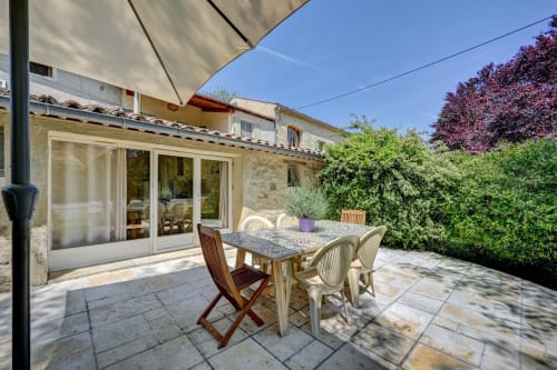 Terrasse ensoleillée du Gîte Lavande au Domaine Bellavigne, Forcalquier, avec table à manger, chaises et haies luxuriantes