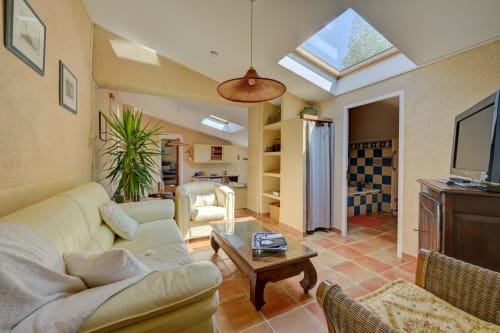 Séjour lumineux du cottage Lavande au Domaine Bellavigne avec puits de lumière, canapé crème, table en bois et vue sur le jardin
