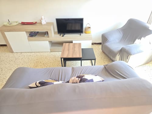 Modern living room in Rosas apartment with gray sofa, TV, wooden furniture, and beige terrazzo flooring