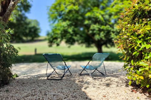 Deux chaises de camping bleues sur gravier dans le jardin luxuriant du Gîte Romarin au Domaine Bellavigne, Forcalquier