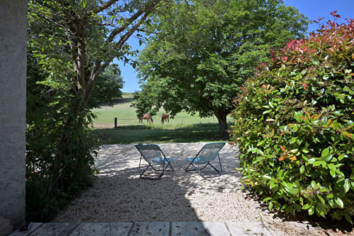 Deux chaises longues sur la terrasse gravillonnée du Gîte Romarin à Forcalquier, vue sur les jardins verdoyants