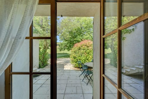 Vue du jardin du gîte Romarin au Domaine Bellavigne, terrasse avec chaise et paysage luxuriant